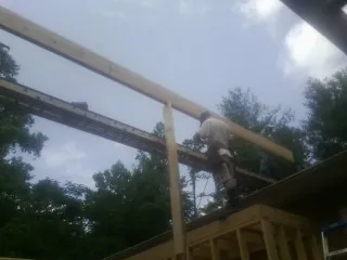 Carpenter setting a ridge beam over a new addition frame — Ice Dam Removal by Roofing Brothers in Keyesport