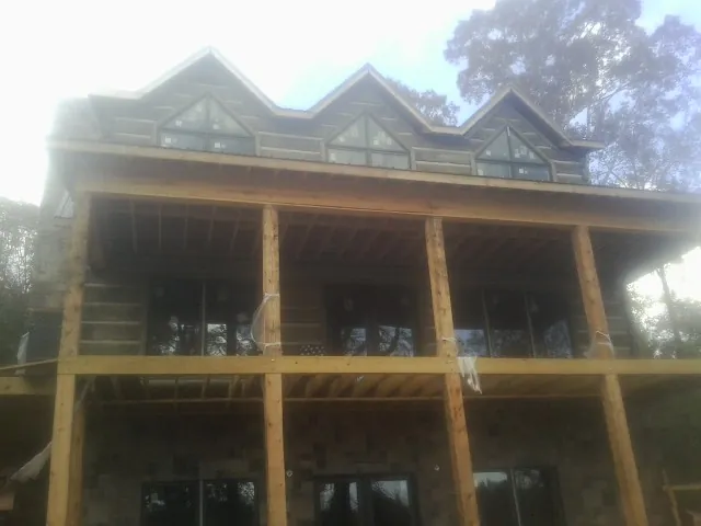 Dormers and porch framing on a large log home under construction — Roof Coating work by our crew in Keyesport