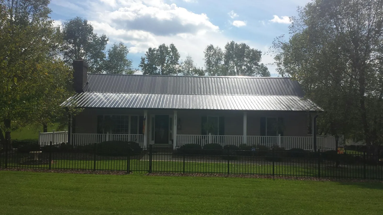 Gray metal roof on a brick ranch with a full width front porch — Gutter Guard Installation work by our crew in Keyesport