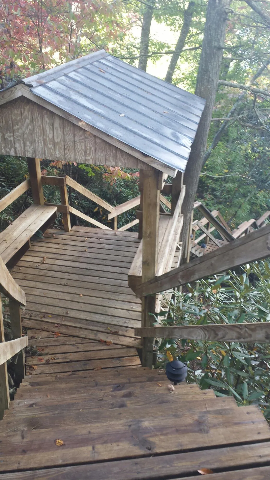 Metal roofed shelter over wooden steps on a wooded walkway — Skylight Repair & Installation work by our crew in Keyesport