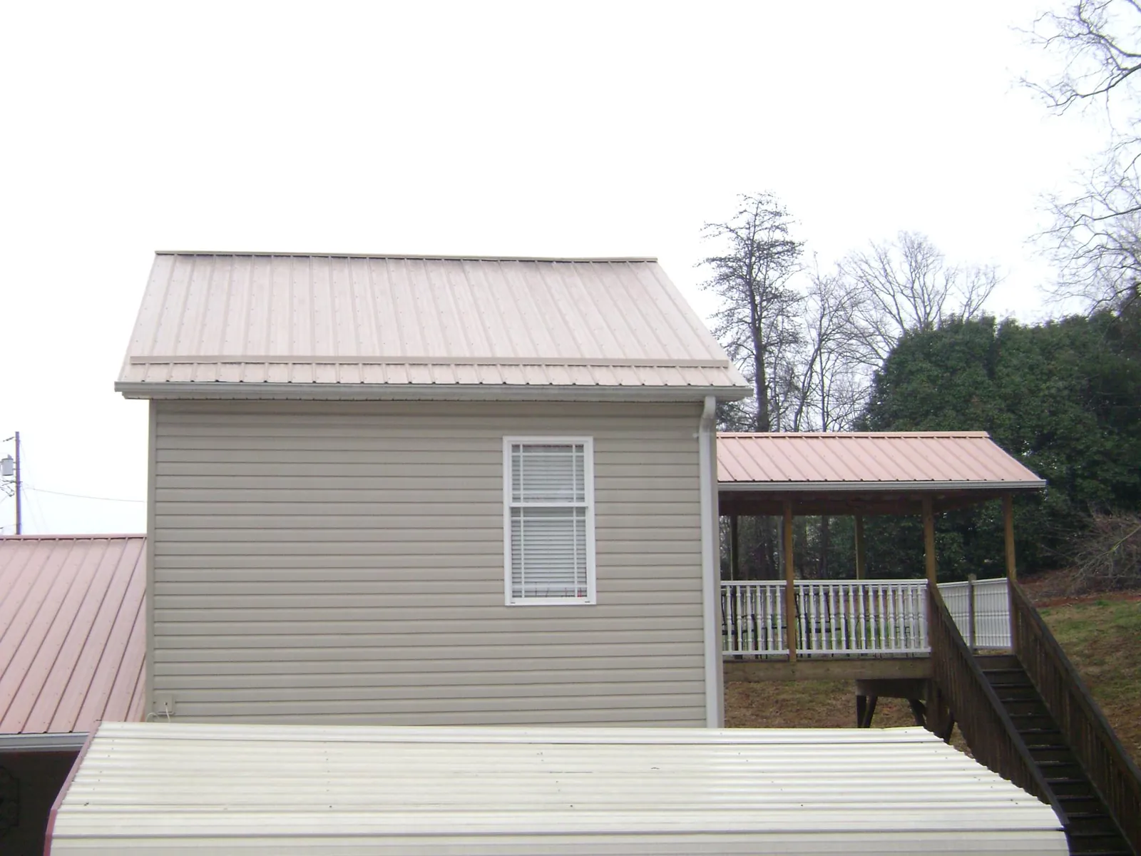 Tan metal roofs on a two story addition and attached porch, from a Roof Replacement job in Keyesport